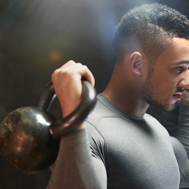 Male athlete exercising with kettle bells