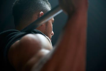 male athlete lifting weight bar black background