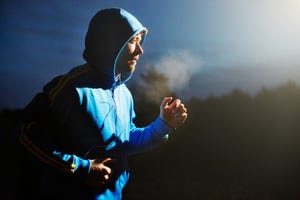 Male athlete running at night with mp3 player.