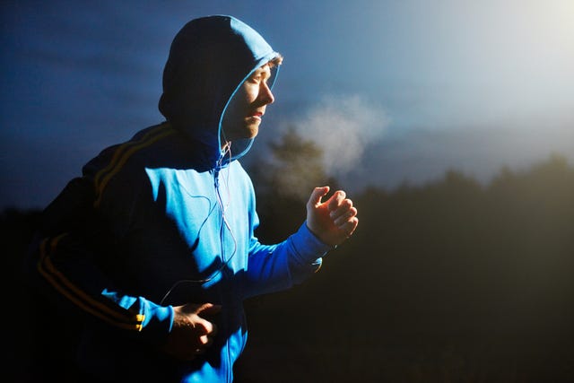 Male athlete running at night with mp3 player.
