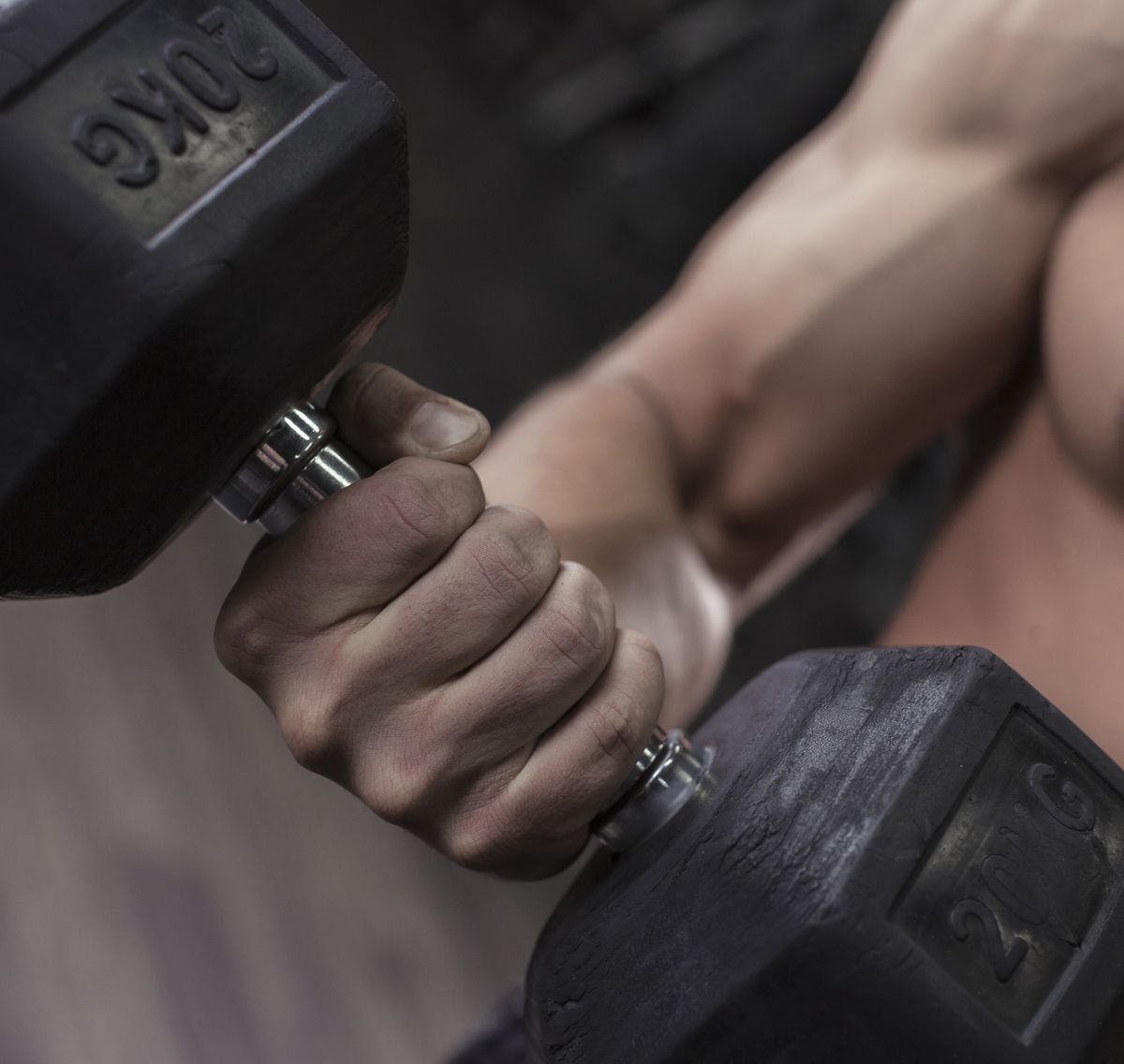 Male bodybuilder holding dumbbell in his hand at gym
