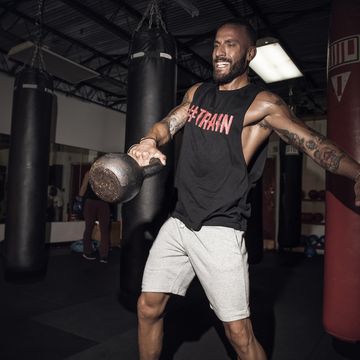 male boxer lifting kettlebell with gritted teeth in gym