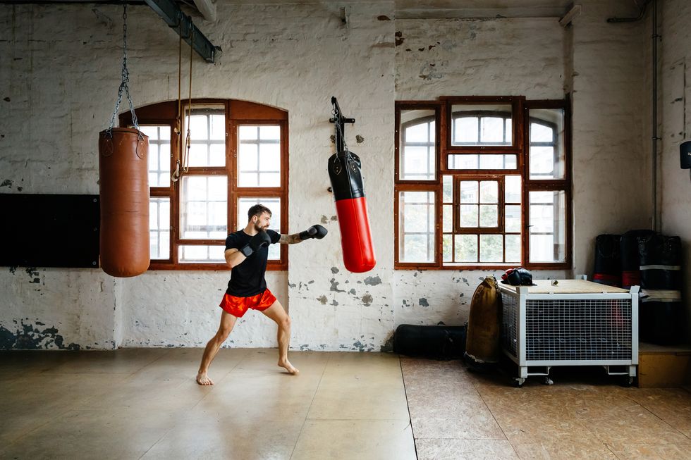 Wall murals Young professional boxer training with punching bag in