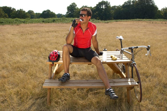 ciclista comiendo sentado en una mesa de picnic