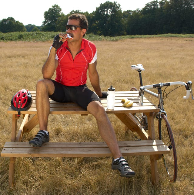 Ciclista comiendo sentado en una mesa de picnic ciclista comiendo sentado en una mesa de picnic