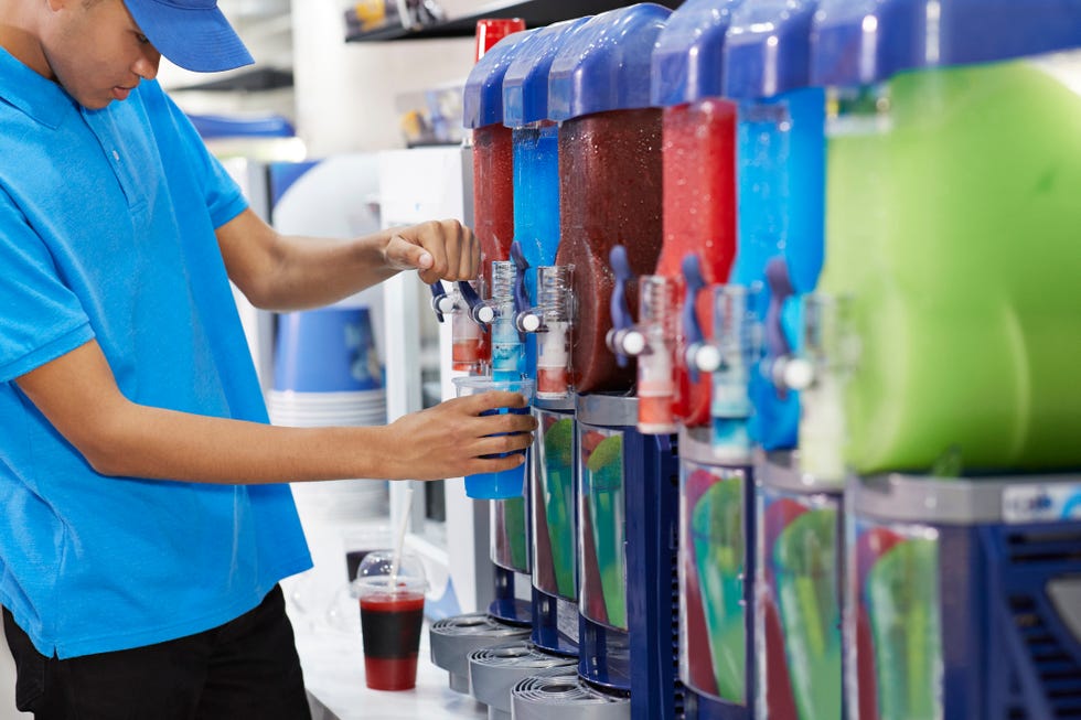 male employee fills lemonade from a machine into a cup