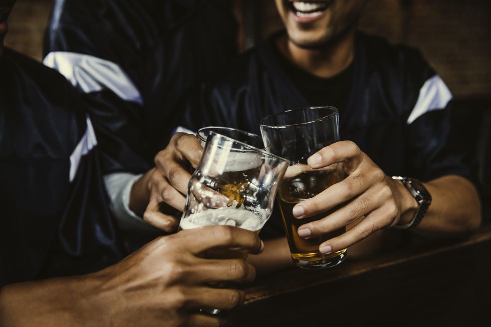 male football fans toasting beer glasses in bar