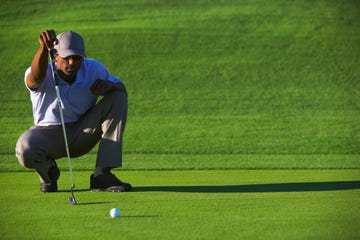 male golfer lining up putt on golf course