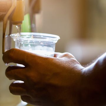 male hand serving water of a water cooler in plastic cup