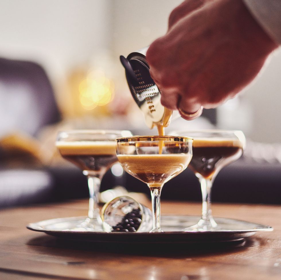male hands pouring espresso martini cocktail into glass