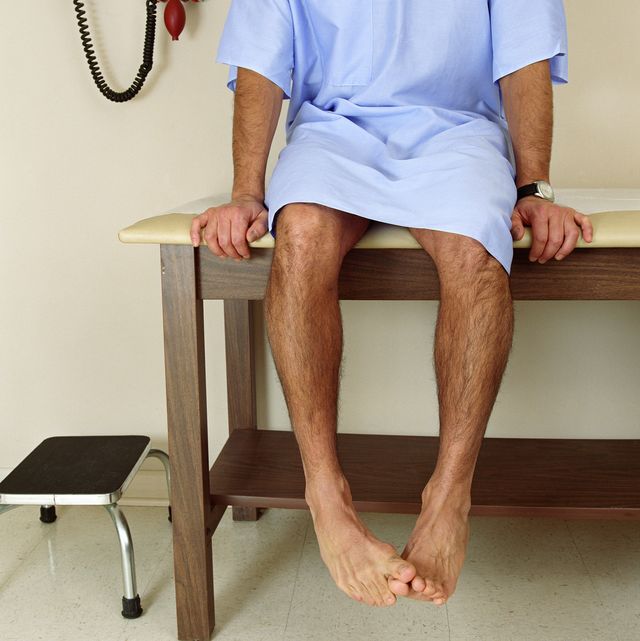 male patient sitting on examining room table, mid section