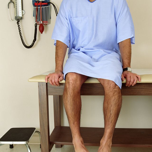 Male patient sitting on examining room table, mid section