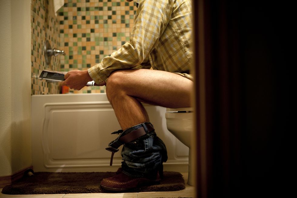 male reading magazine on toilet