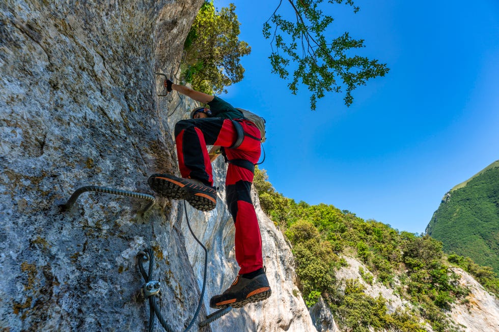 male rock climber ascending steep wall in apennine mountains