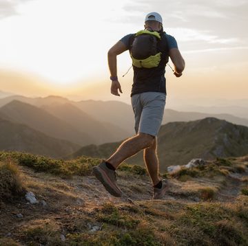 male runner is jogging on the ridge of a mountain.
