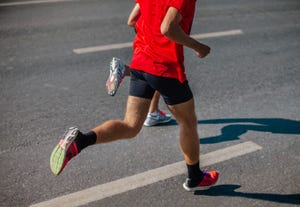 male runner running marathon running on gray asphalt