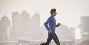 Male runner running on sunny urban street