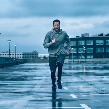 male runner runs on wet streets after rain