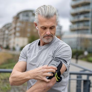 male runner using an arm band for his cell phone while running outdoors