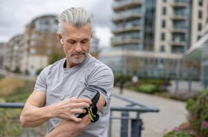 male runner using an arm band for his cell phone while running outdoors