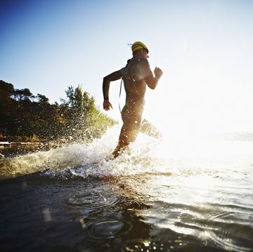 male triathlete running into water at sunrise