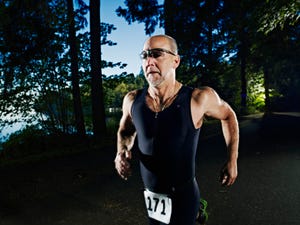 male triathlete running race on path through woods