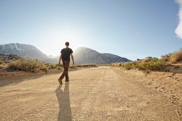 male walking up dirt road into the light