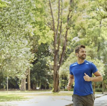 male with in ear headphones jogging in park