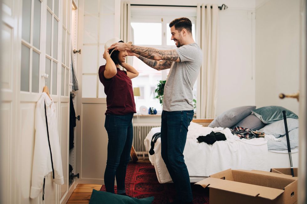 man adjusting hat on woman at bedroom during relocation