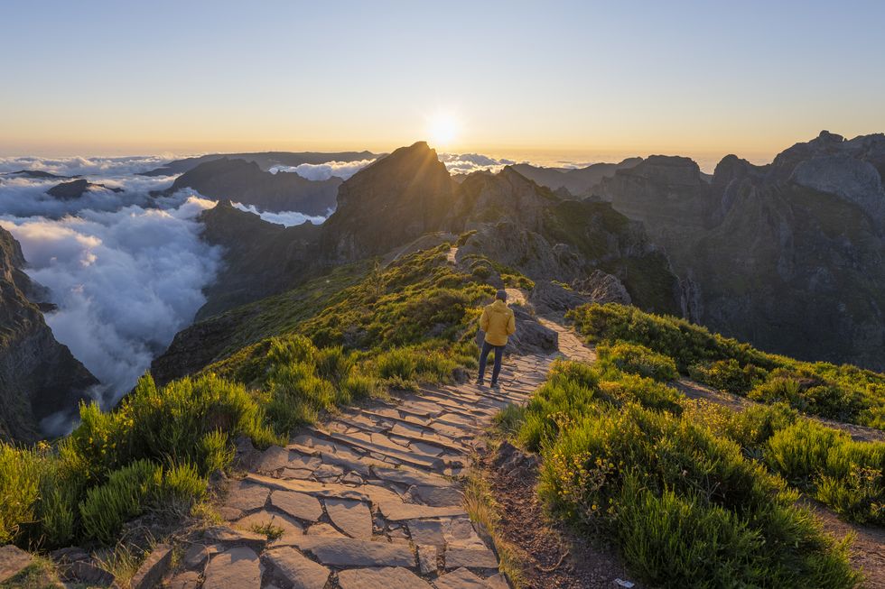 een man loopt over de wandelroute bij pico do arieiro op madeira tijdens zonsondergang