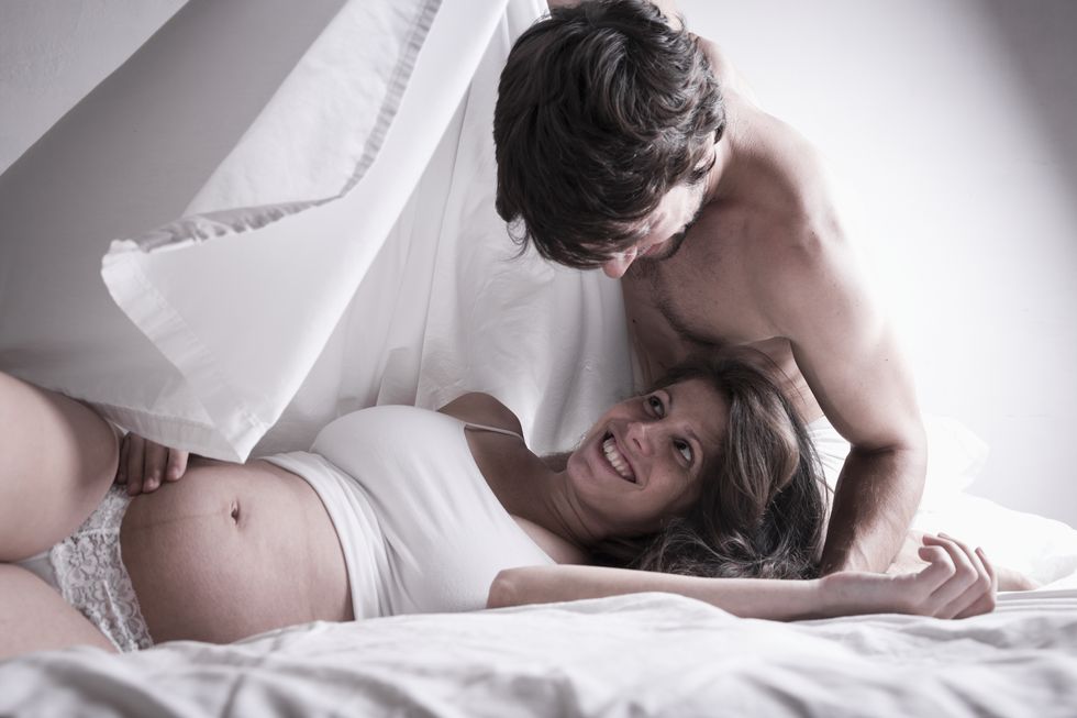 Man and pregnant woman flirting in bed