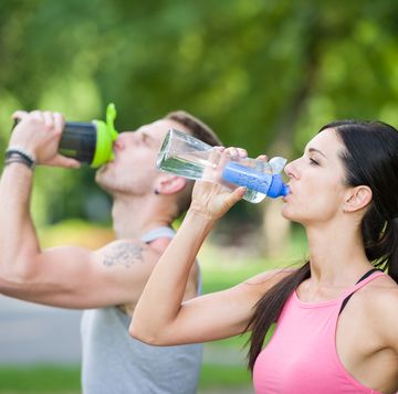 man and woman drinking water in a park in summer
