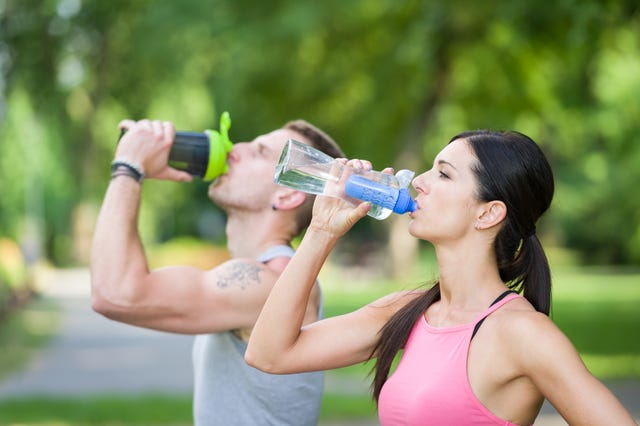 man and woman drinking water in a park in summer