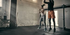 man and woman in gym jumping in mid air