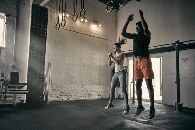 man and woman in gym jumping in mid air