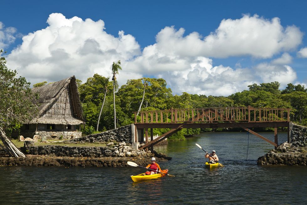 man and woman kayaking through the protected mangrove areas near men's house in yap, micronesia