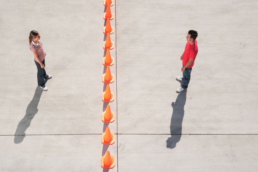 man and woman on either side of row of traffic cones looking back