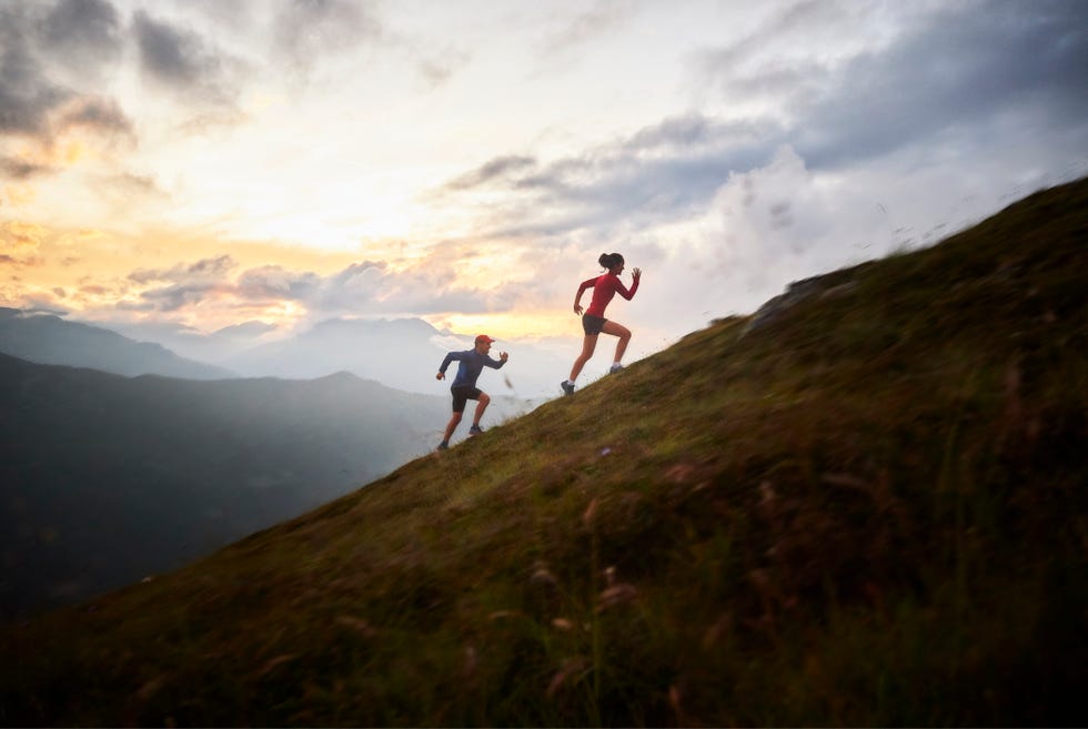 man and woman running uphill in the mountains