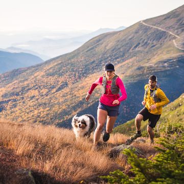 man and woman trail SL20.2 running with dog in mountains at sunrise
