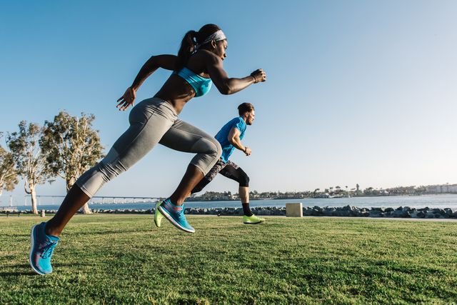Man and young woman training, sprinting on coast, downtown San Diego, California, USA