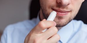 man applying hygienic lipstick on lips to revive chapped lips and avoid dry, closeup