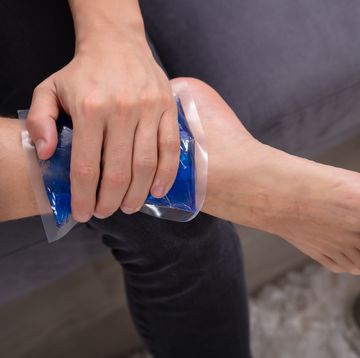 man applying ice gel pack on an ankle