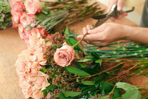 Man assistant in flower shop delivery make rose bouquet closeup