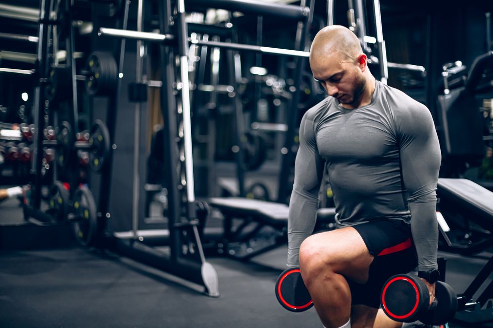 man athlete exercising with dumbbells in a lunge position at gym
