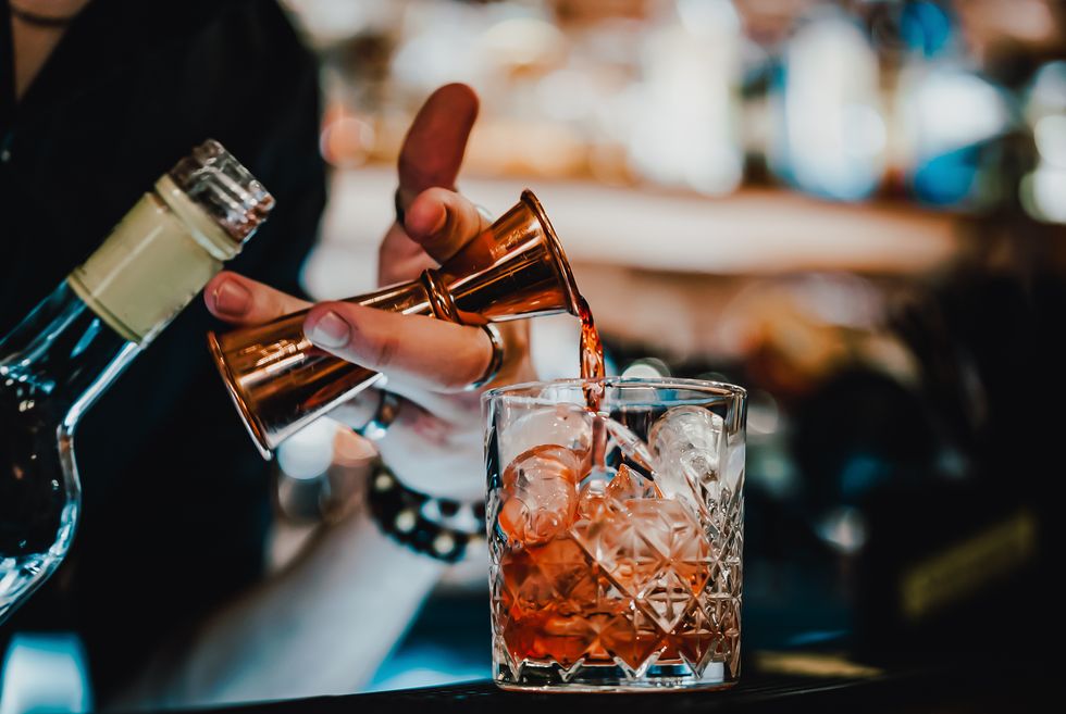 man bartender hand making negroni cocktail. negroni classic cocktail and gin short drink with sweet vermouth, red bitter liqueur
