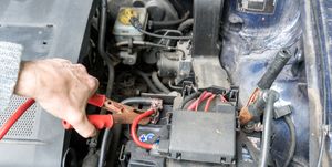 Man charging a car battery with a jumper cable