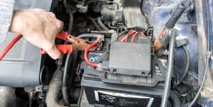 Man charging a car battery with a jumper cable