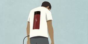man charging battery in back with plug, standing at electric outlet