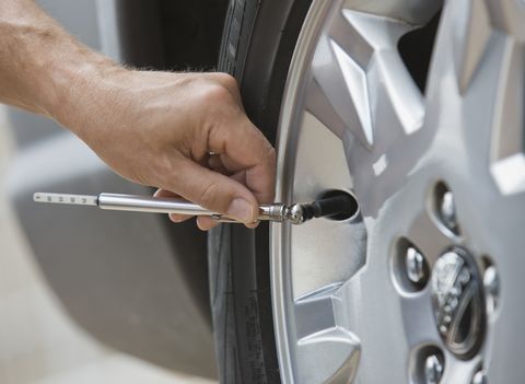 person's hand holding a tool to check tire pressure