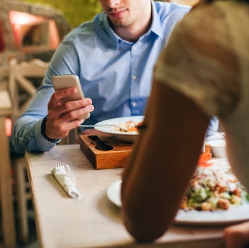 man checking messages while having dinner in a restaurant